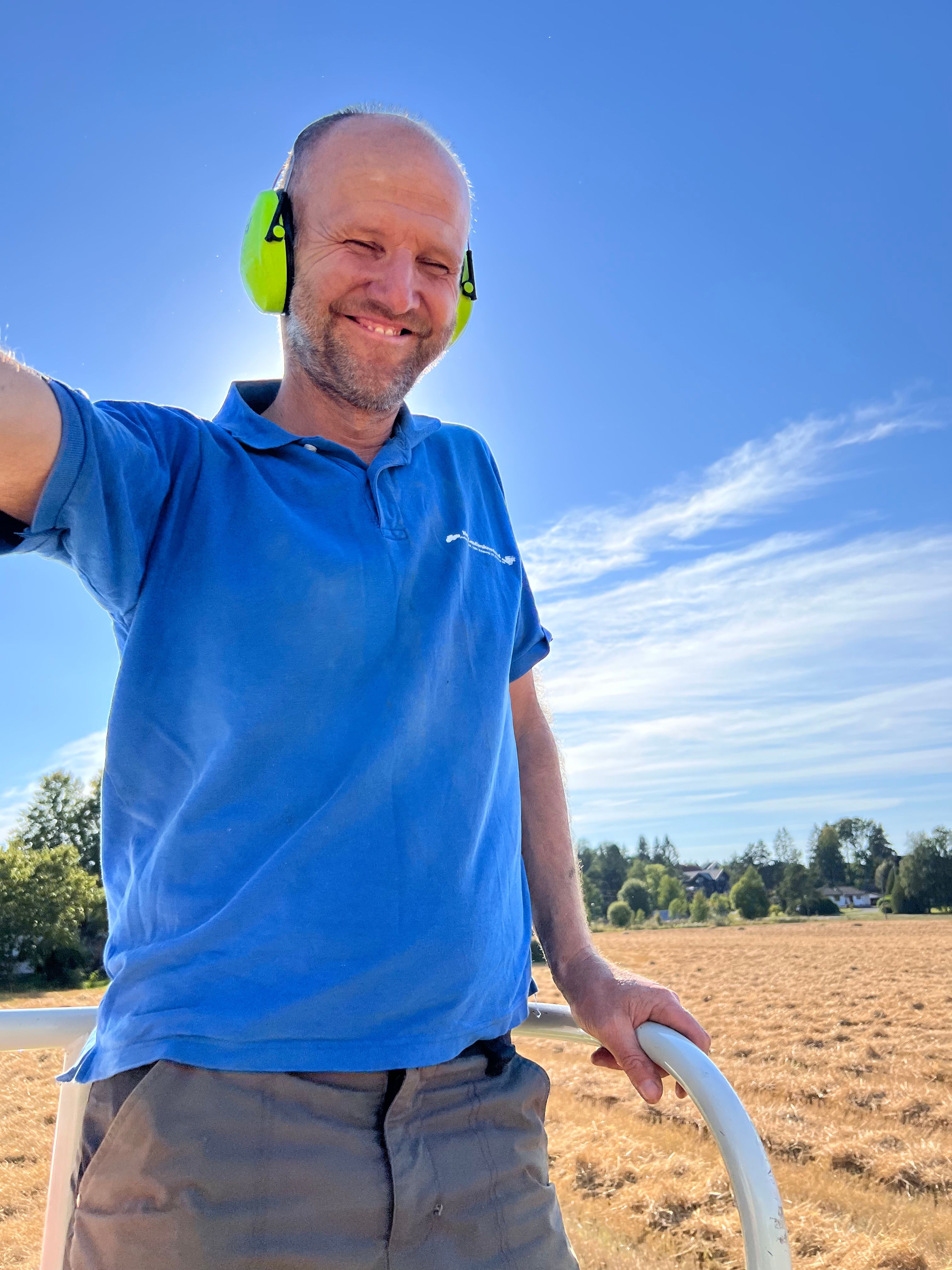 Olav Røyneberg på treskeren, stort smil. 