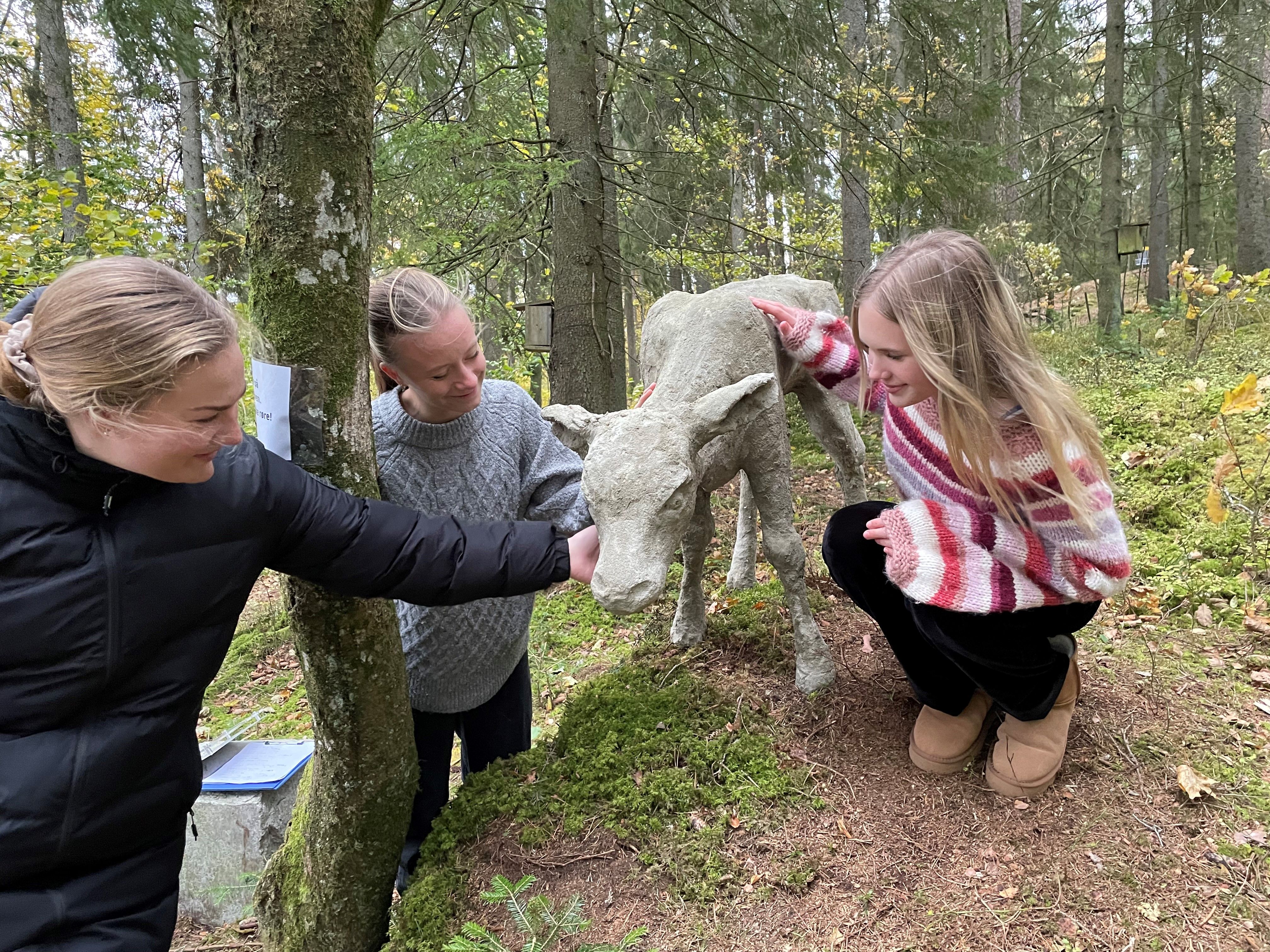 Tre elever betrakter skulpturen kalven, utplassert i Tomb-parken.