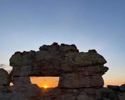 Solnedgang mellom steinsiluett.