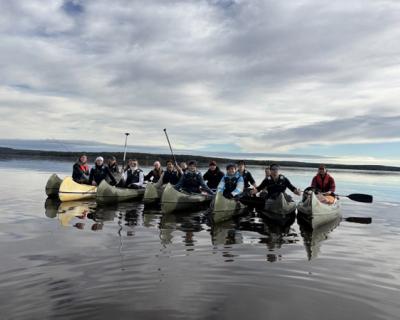 Elever i kanoer på stille vann.
