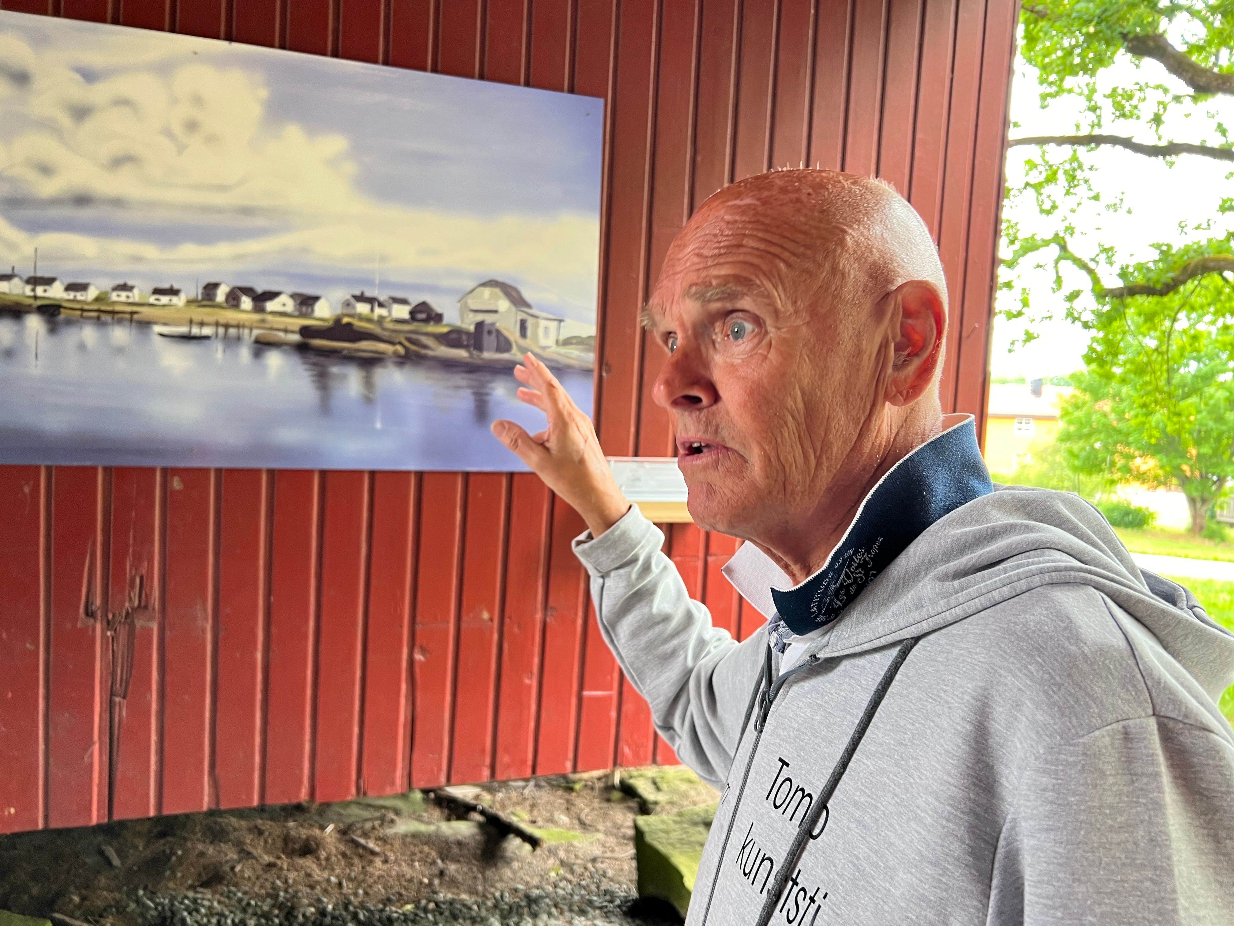 Leder i Kunstforeningen orienterer om bildet "Saltholmen" som henger på en vegg.