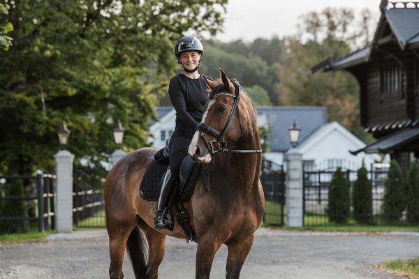 Henriette sitter på en hest, smiler mot kamera