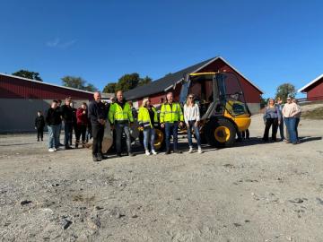Elever og ansatte står foran en hjullaster ute på en åpen plass