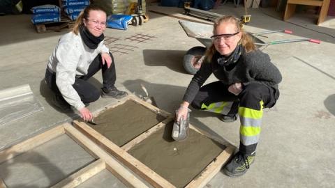 To jenter som støper smiler i kamera.