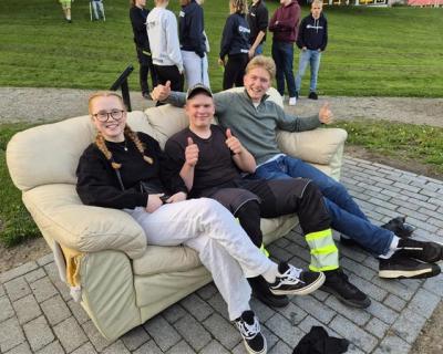 3 elever sitter i en sofa i parken