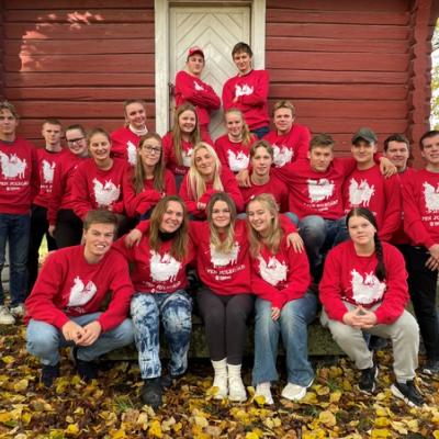 Klasse oppstilt foran et stabbur. Alle elevene har røde Åpen Julegård-gensere.