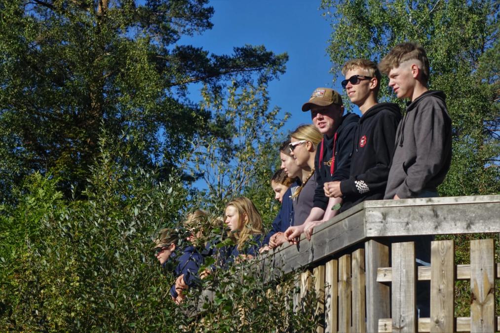 Voksne elever står på en veranda.