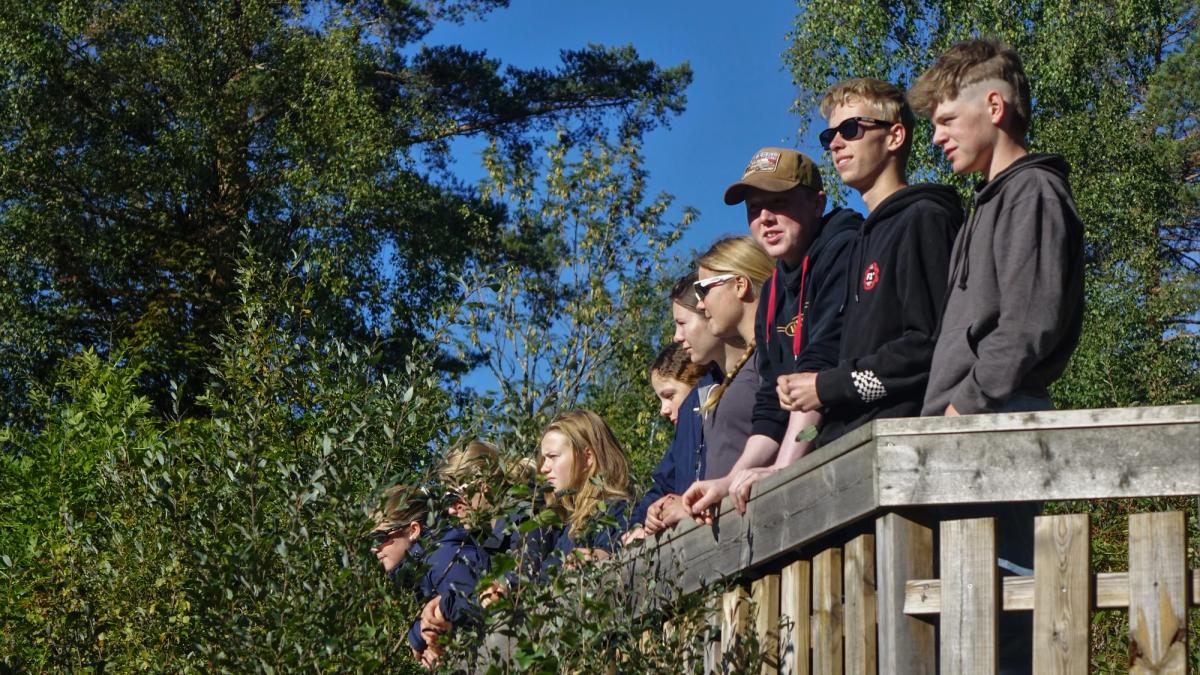 Voksne elever står på en veranda.
