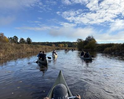 Elever padler i kano på en elv.