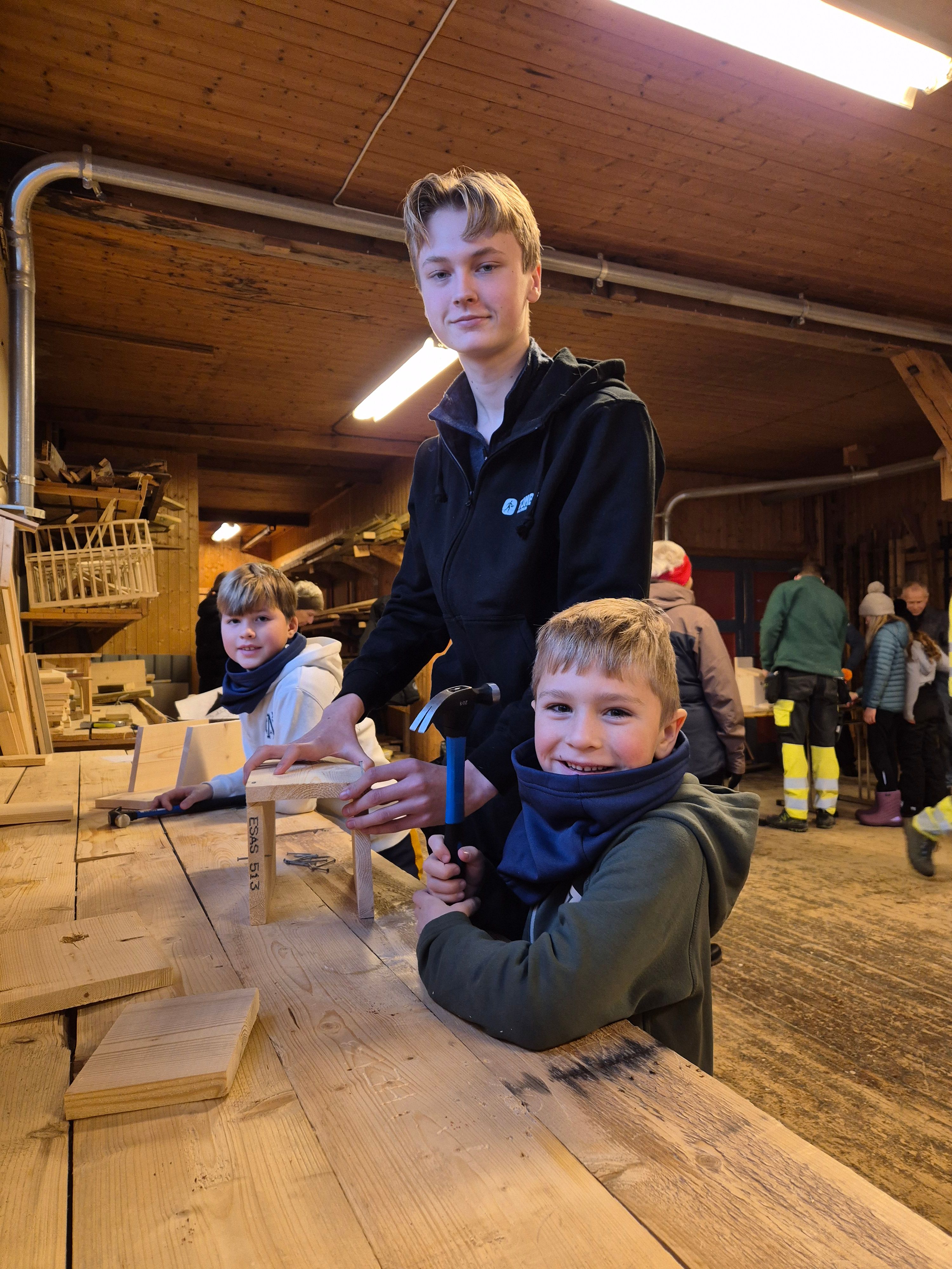 Elev som snekrer fuglekasser med to barn