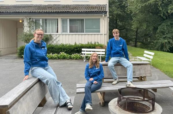 3 ungdommer sitter på benker. Alle har blå hettegenser.