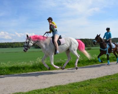 To elever som hver sin hest på grusvei.