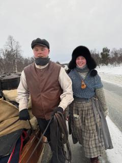 Ung mann og ung kvinne går med hest og slede. Klær med inspirasjon fra 1800-tallet.