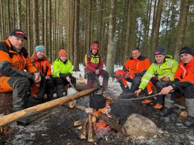 Elever rundt et bål i skogen.