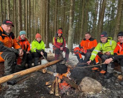 Elever rundt et bål i skogen.