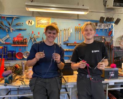 To gutter som strikker i verkstedet. 