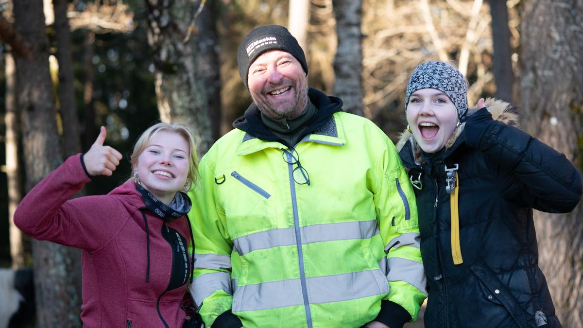 Lærer i midten, glade elever med tommel opp på hver side