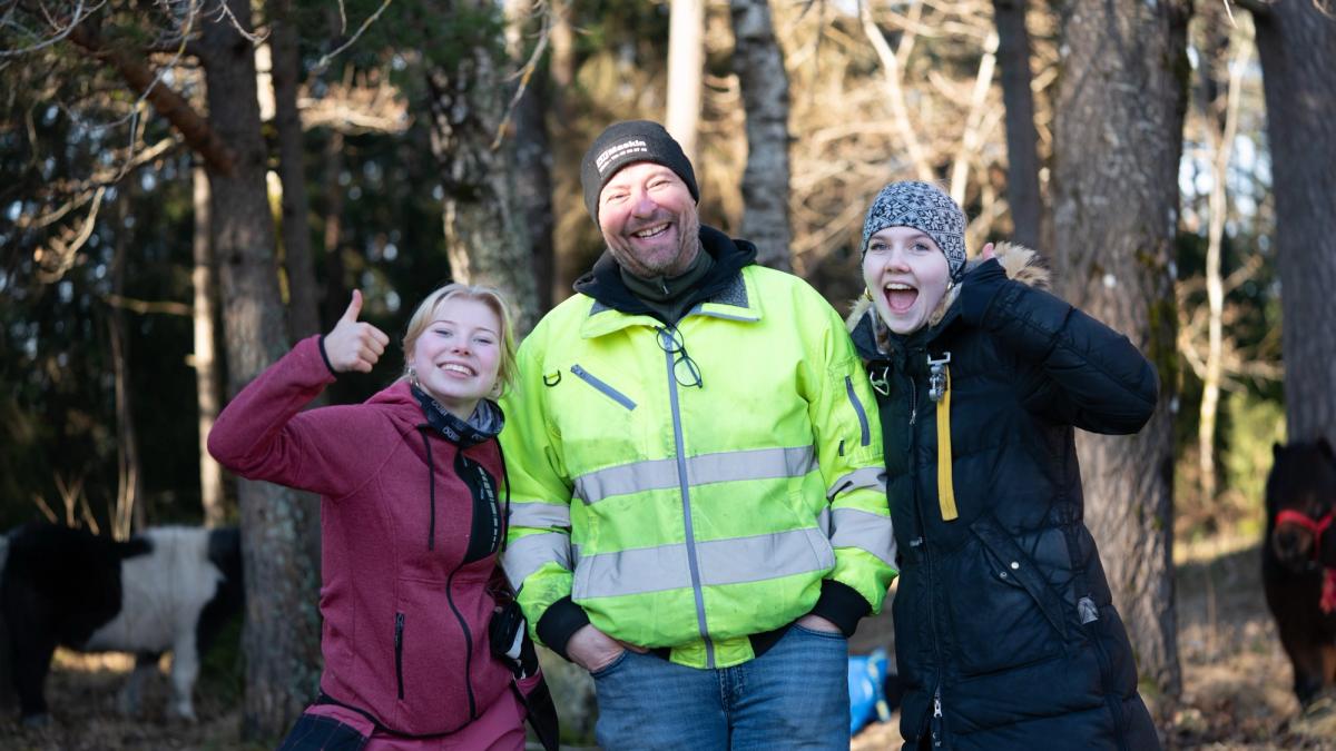 Lærer i midten, glade elever med tommel opp på hver side