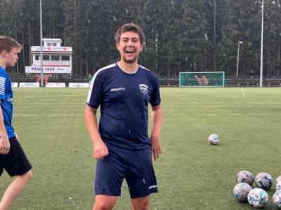 Fotballspiller i snøvær på fotballbanen - smiler mot kamera