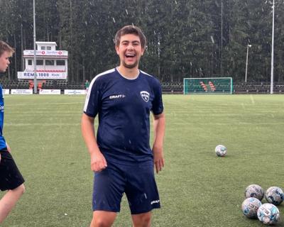 Fotballspiller i snøvær på fotballbanen - smiler mot kamera