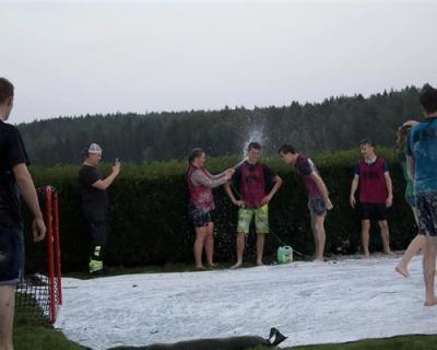 Flere elever samlet i parken. Et par elever spyles med slange