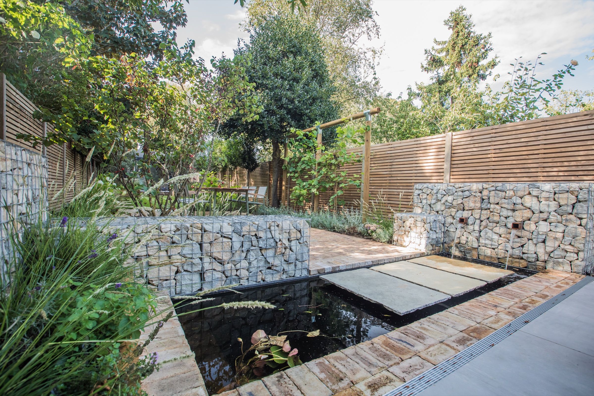 Formal rear garden with layered planting, stonework and water
