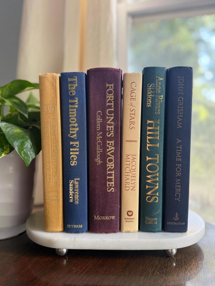 Curated collection of rich brown, hunter green, deep navy, and warm ivory books with classic gold accents.
