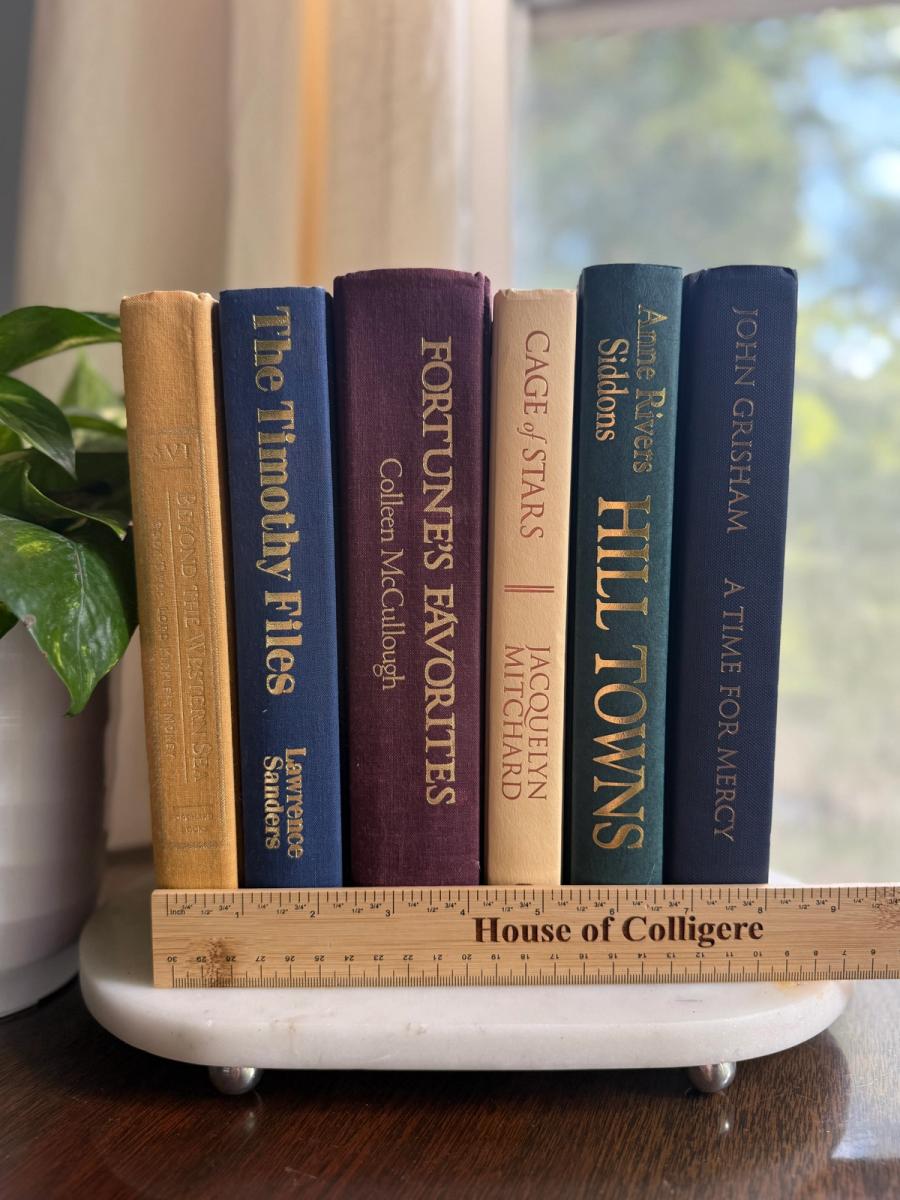 Curated collection of rich brown, hunter green, deep navy, and warm ivory books with classic gold accents.