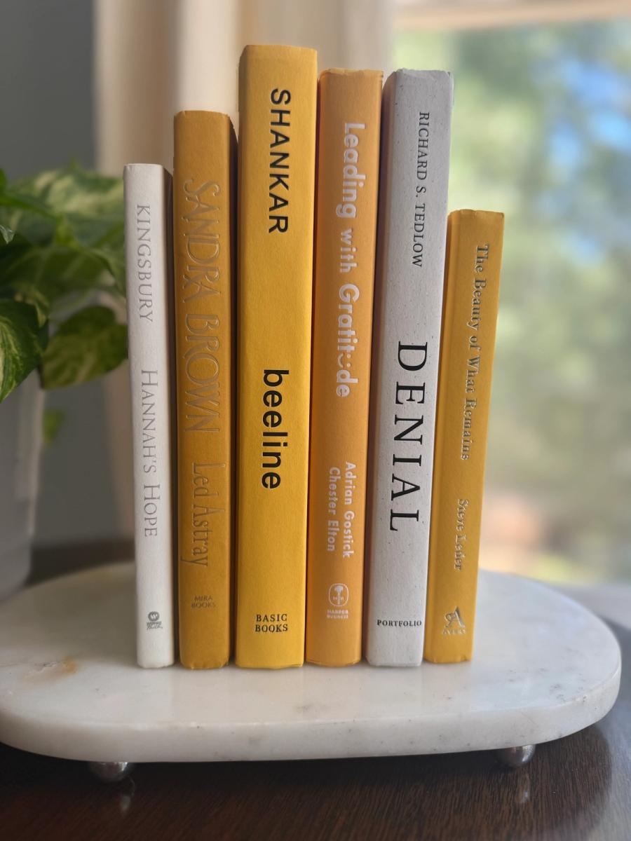 Six curated hardcover books in mustard yellow, golden ochre, cream, and soft white tones, tied with natural linen ribbon and displayed with a House of Colligere Modernist Edit No. 5 card.