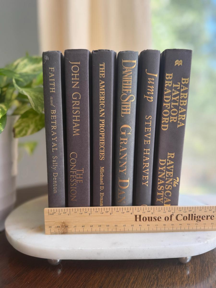 Curated collection of rich charcoal and black books with warm gold lettering and dramatic tonal depth.