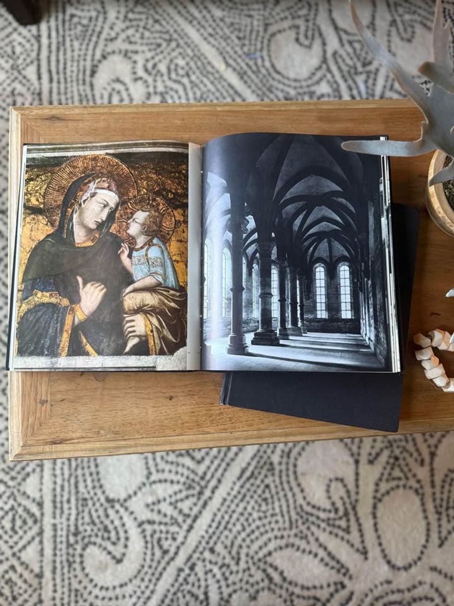 Curated pair of oversized black hardcover books with deep charcoal-black covers, warm aged page edges, and understated gold and cream lettering.