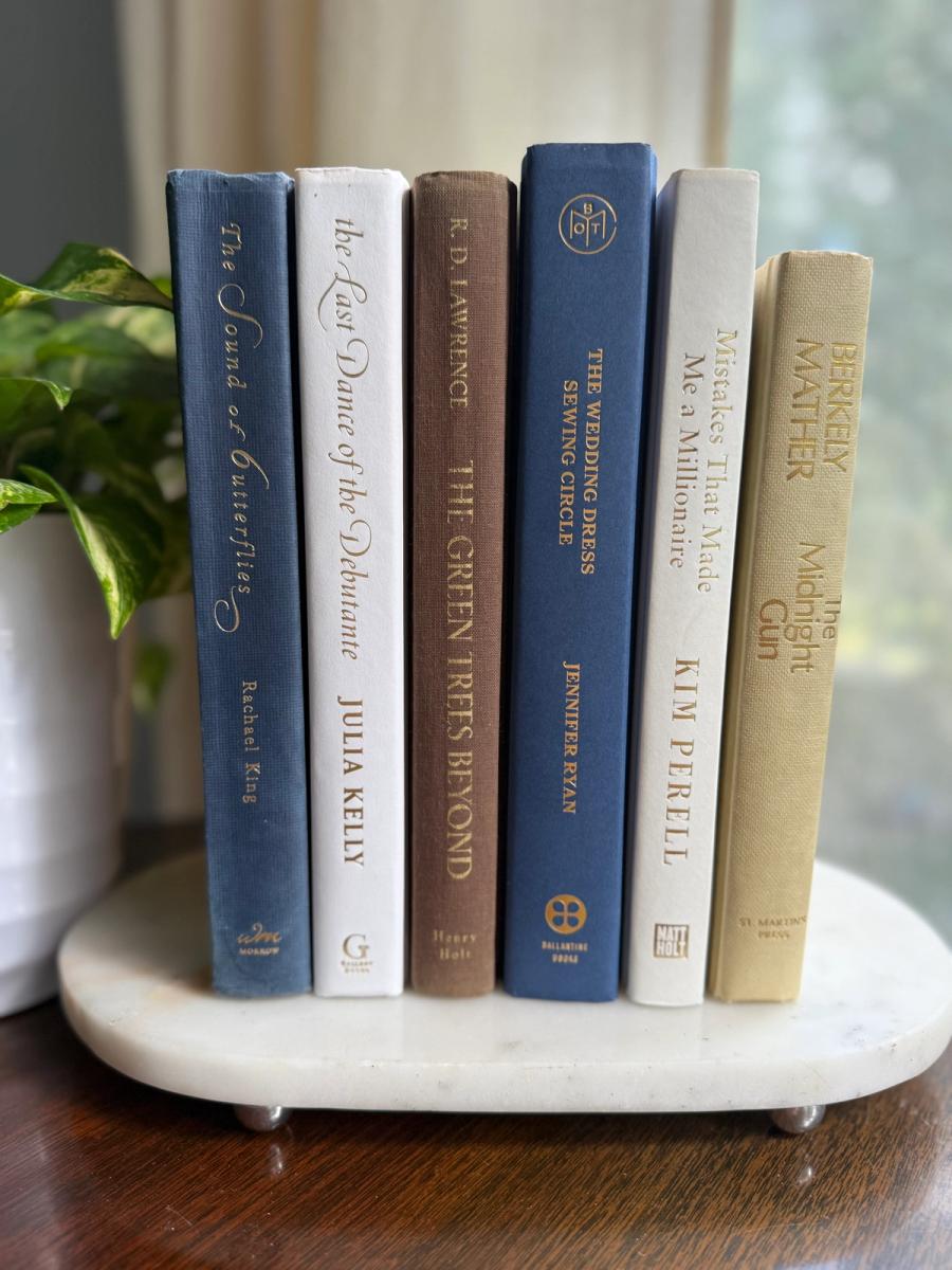 Curated collection of weathered blue, oyster, sand, linen, and driftwood-toned books with soft coastal character.