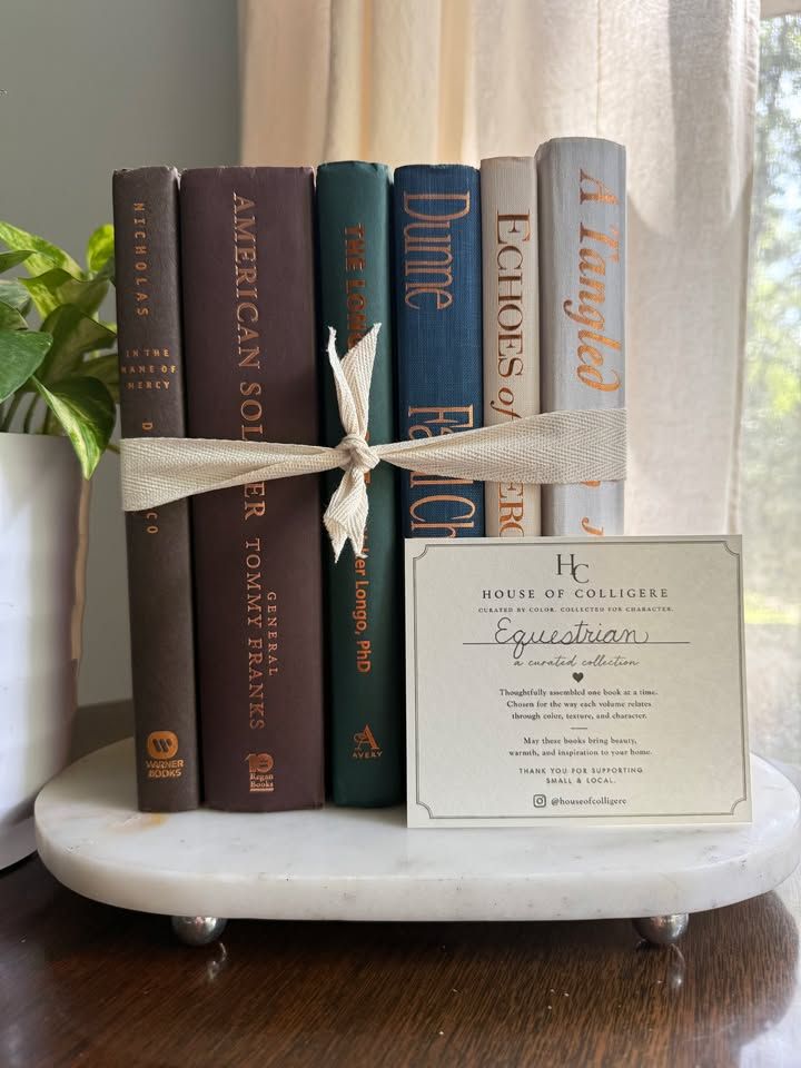 Curated collection of rich brown, hunter green, deep navy, and warm ivory books with classic gold accents.