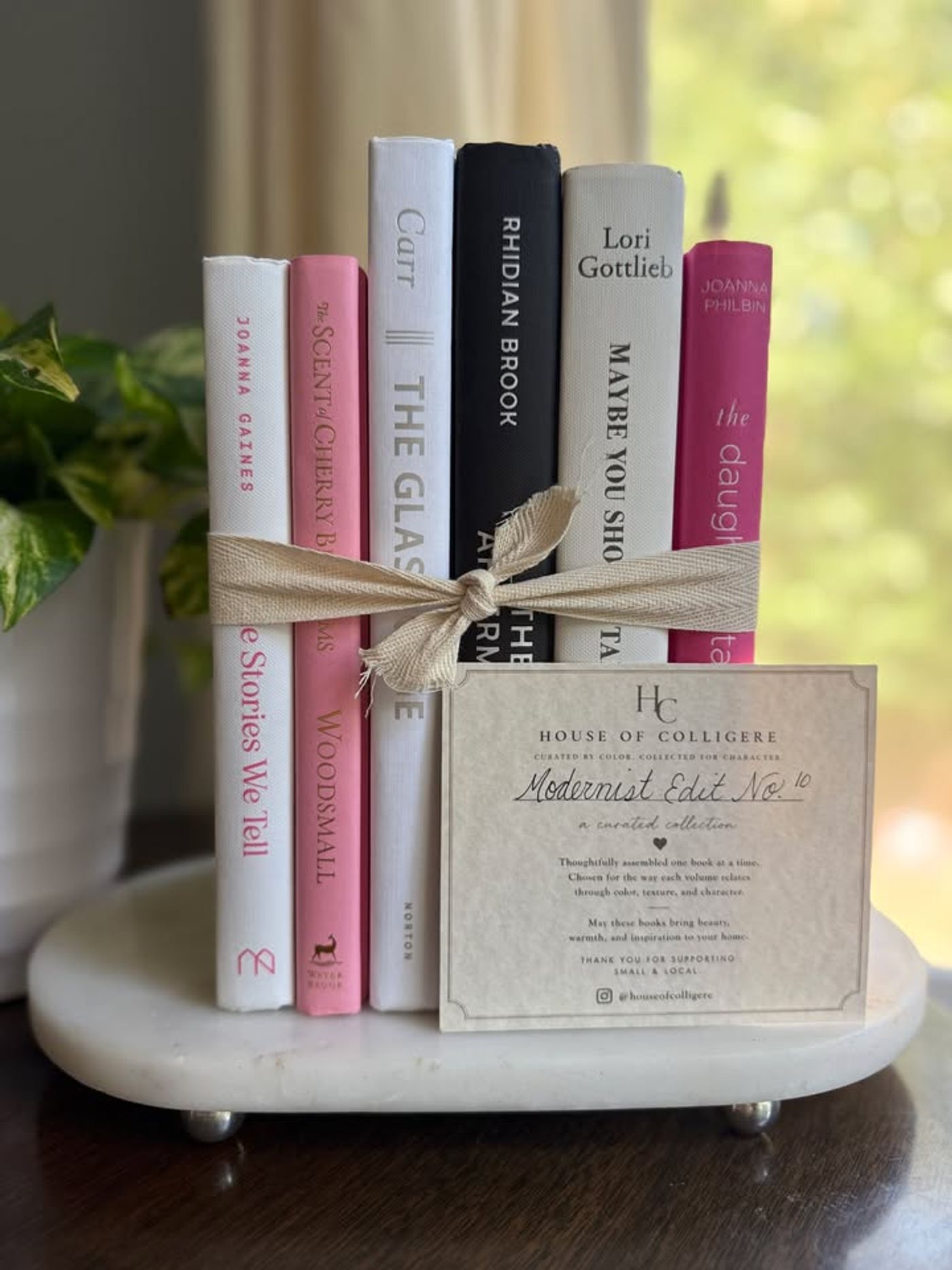 Modernist Edit No. 10 decorative book collection in white, blush pink, black, and raspberry tones, tied with neutral linen ribbon and styled on a marble table.