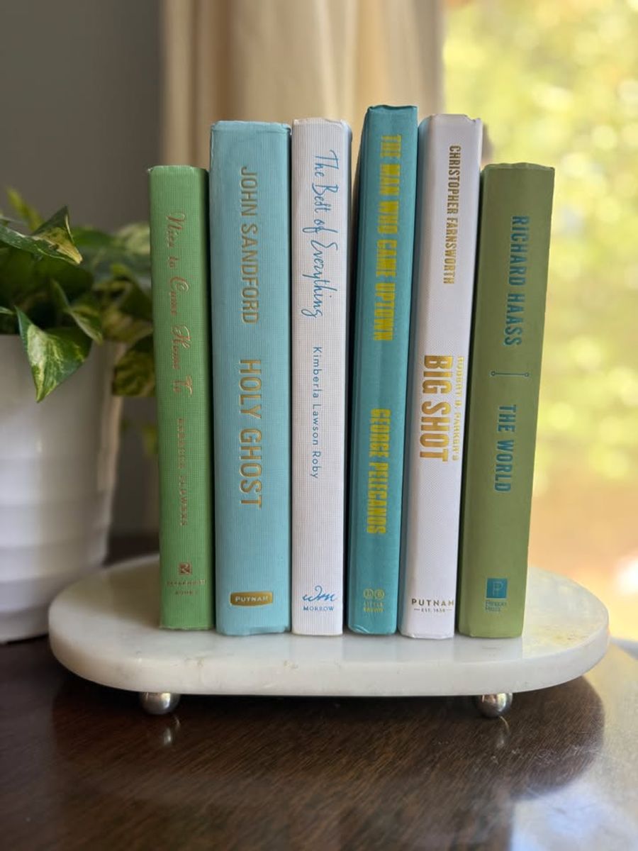 Modernist Edit No. 11 decorative book collection in fresh green, aqua, teal, ivory, and olive tones, tied with neutral linen ribbon and styled on a marble table.