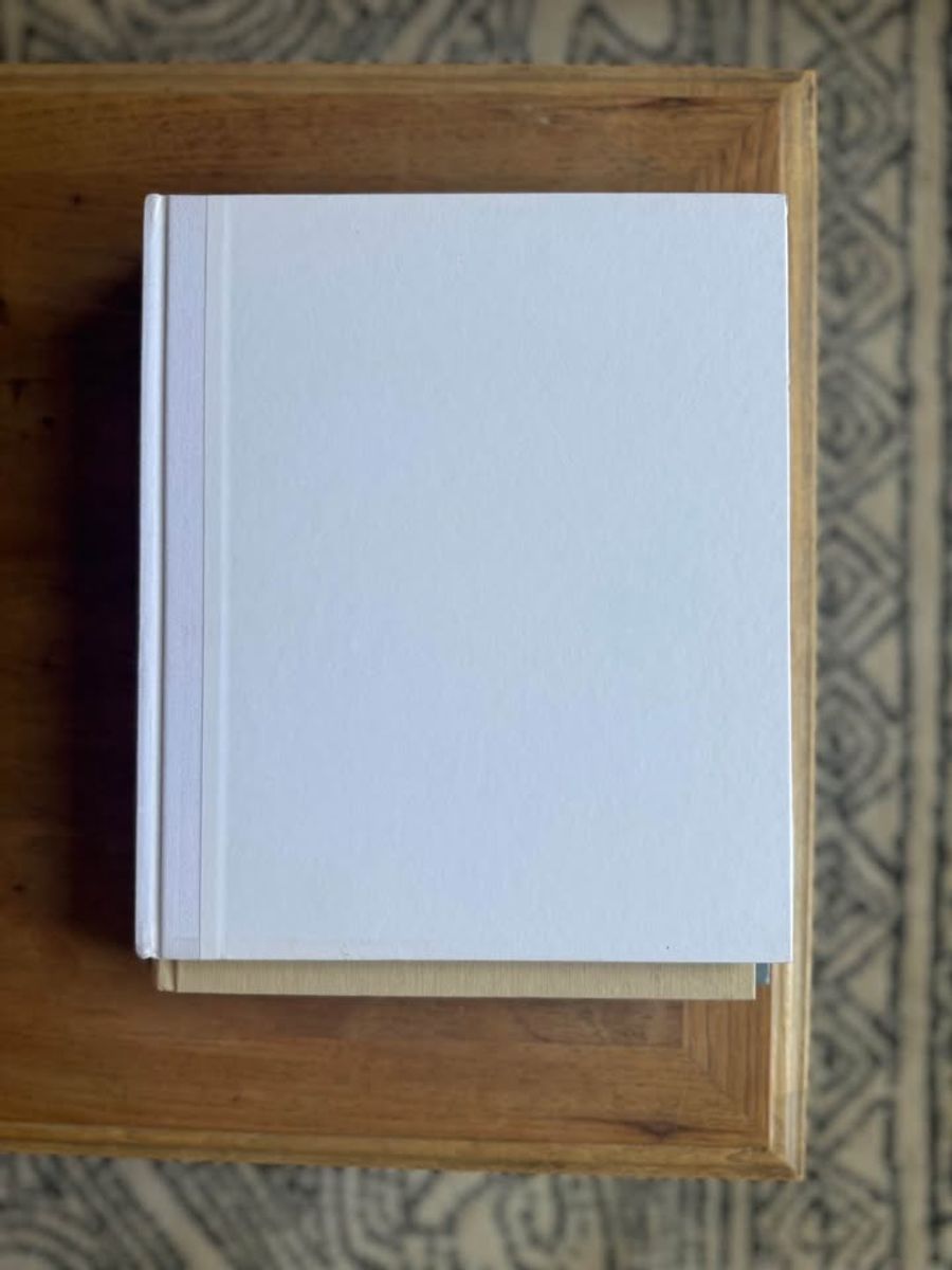 Cream, ivory, warm flax, beige, muted blue-gray, soft taupe undertones, linen-like cloth covers, matte woven texture, subtle gold and metallic lettering, understated traditional styling