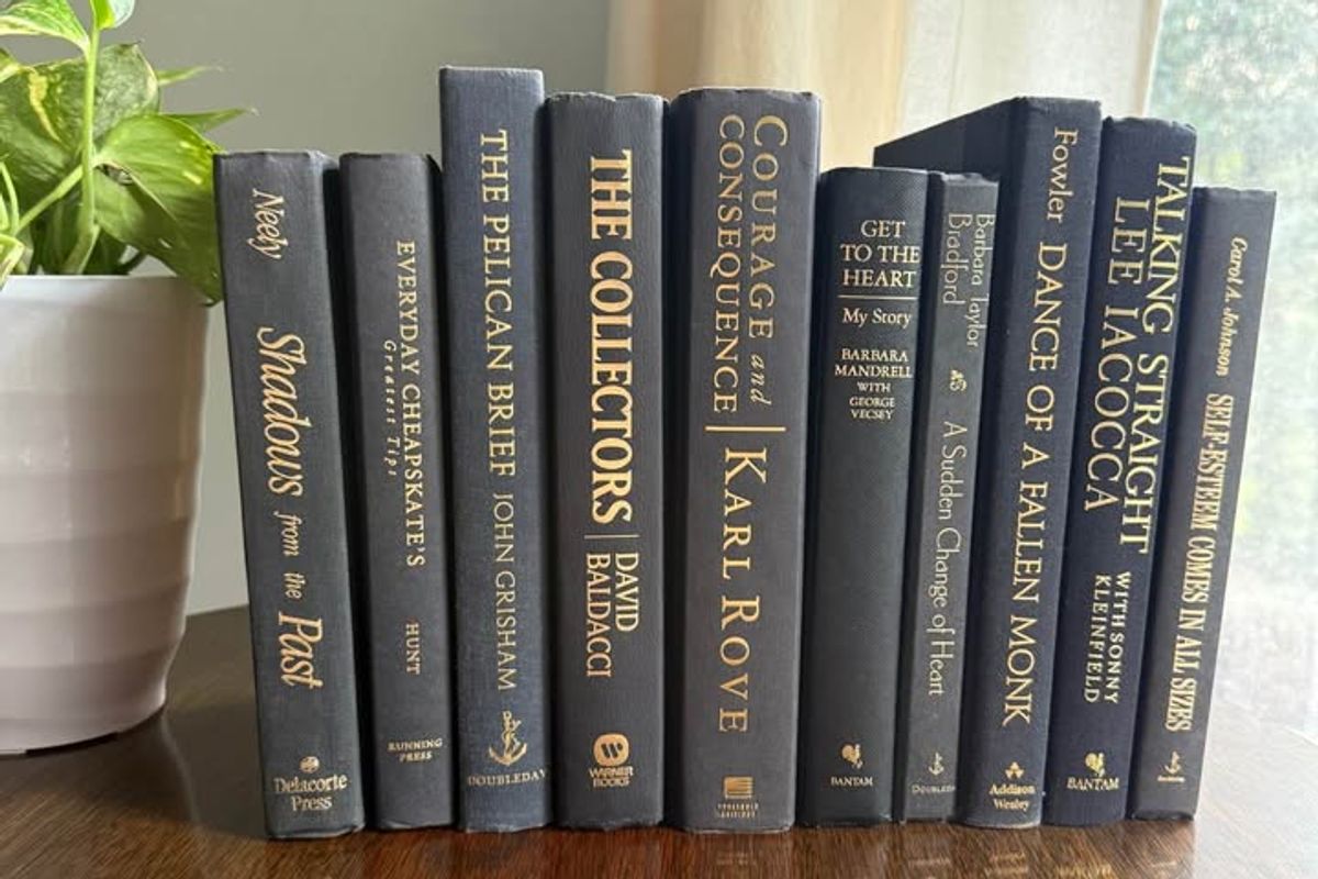 Curated collection of rich charcoal and black books with warm gold lettering and dramatic tonal depth.