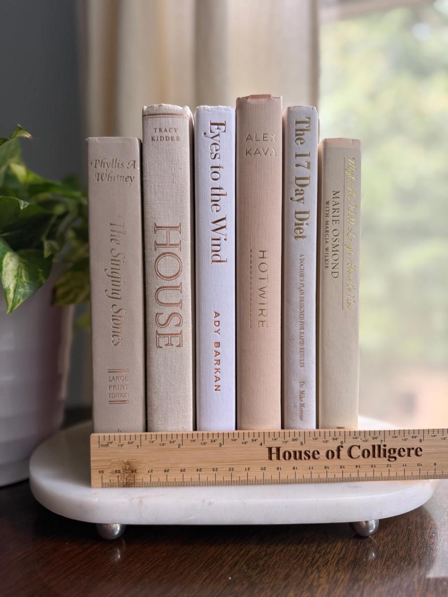 Six white, ivory, and pale taupe hardcover books tied with natural ribbon on a marble tray, with gold-toned lettering and a Linen No. 10 card.