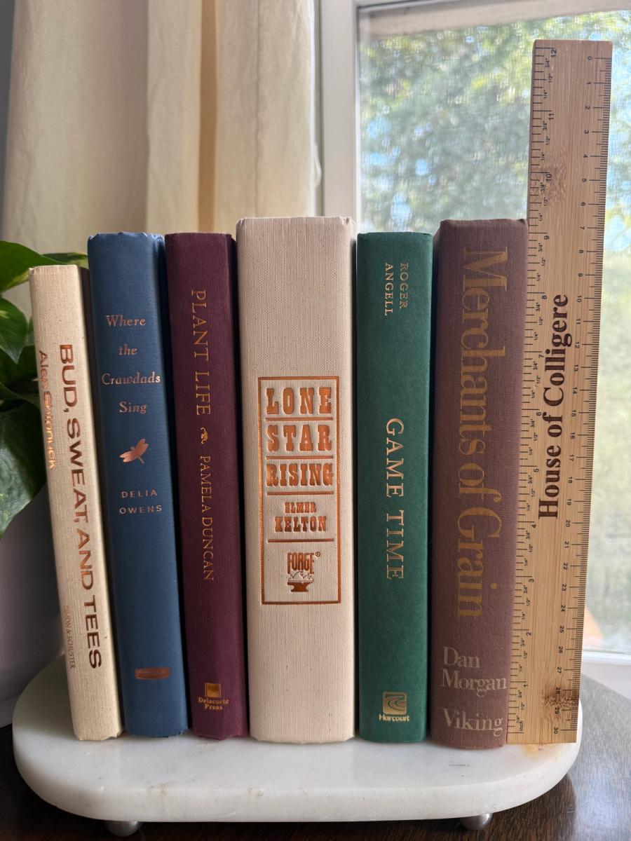Curated collection of rich brown, hunter green, deep navy, and warm ivory books with classic gold accents.