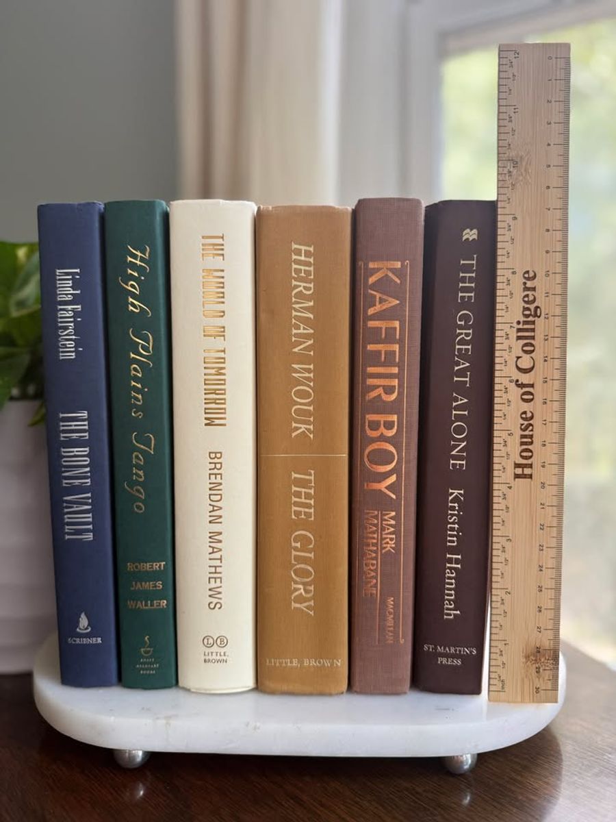 Curated collection of rich brown, hunter green, deep navy, and warm ivory books with classic gold accents.