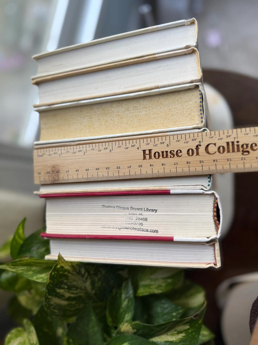 Curated collection of white, ivory, and cream hardcover books with soft neutral tones on a coffee table beside a plant