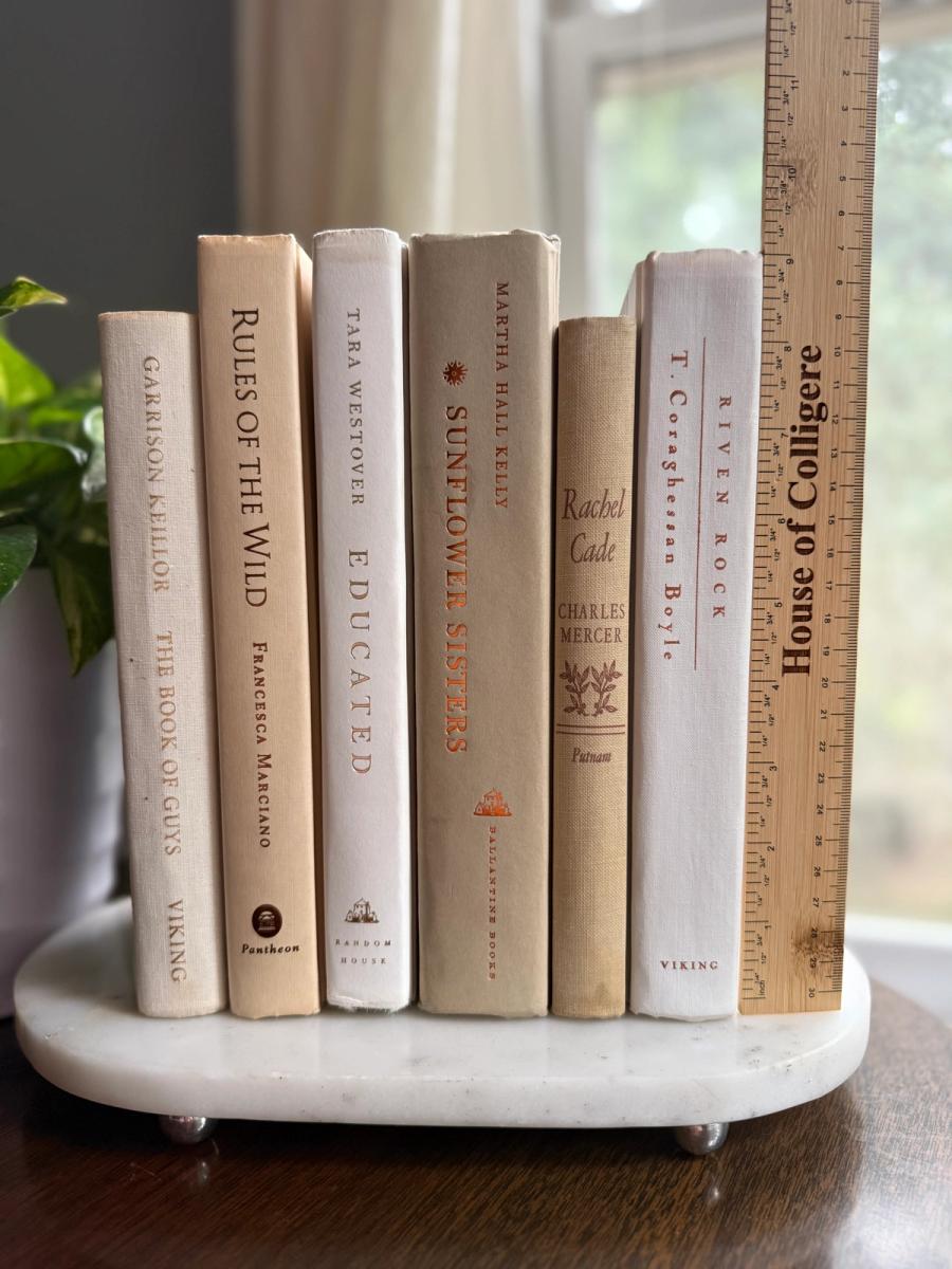 Curated decorative book collection in soft linen-inspired neutrals, featuring ivory, cream, warm beige, and pale taupe clothbound hardcovers with subtle gold, brown, and muted typography.