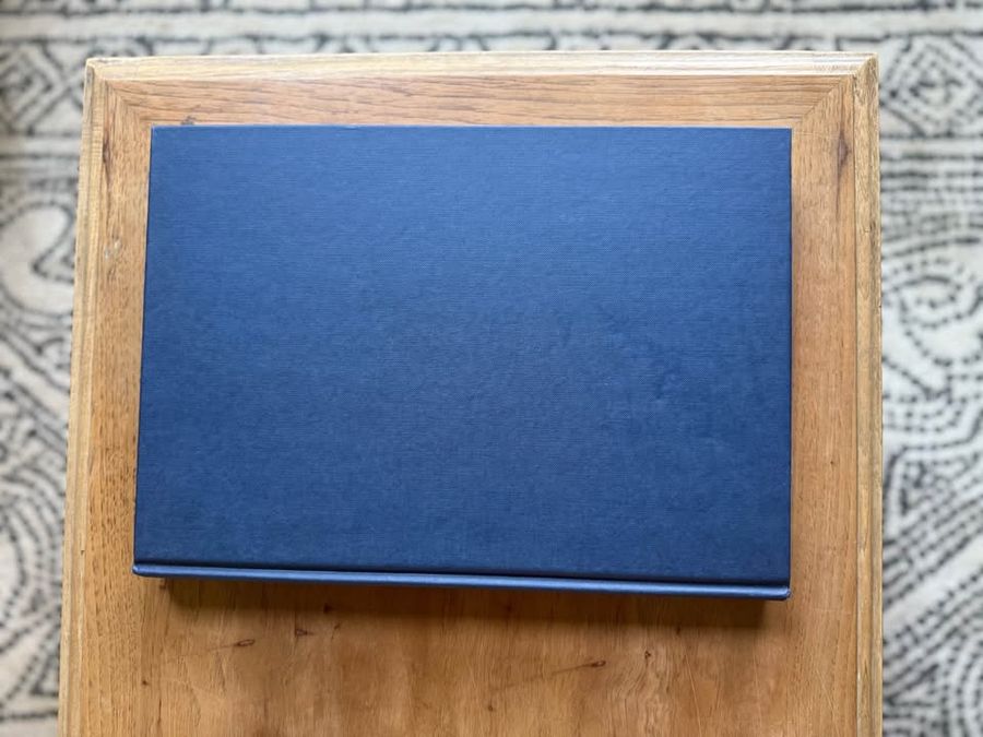 Blue, linen-like cloth covers, matte woven texture, subtle gold and metallic lettering, understated traditional styling