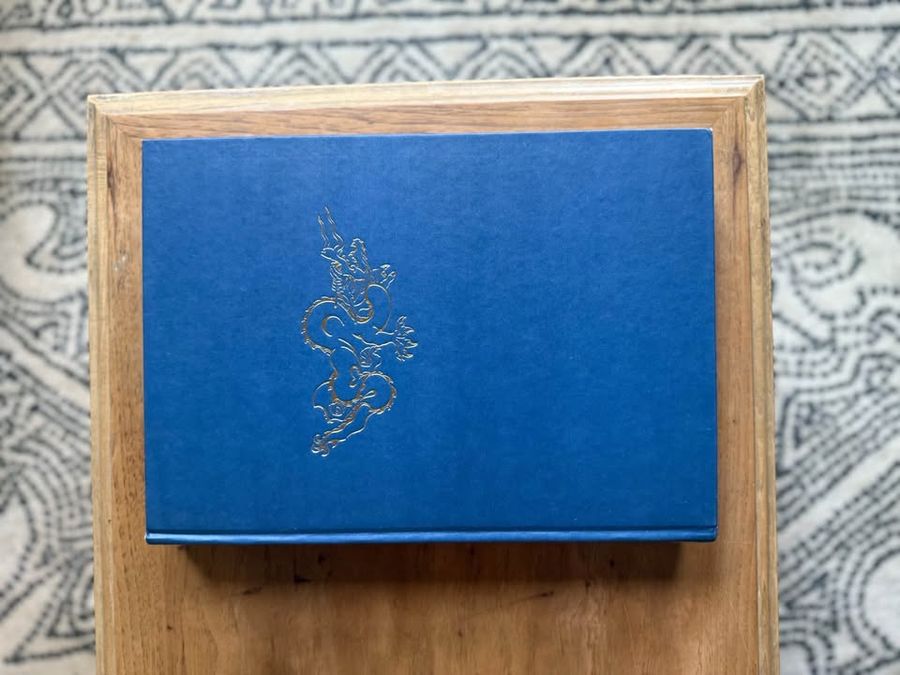 Blue, linen-like cloth covers, matte woven texture, subtle gold and metallic lettering, understated traditional styling