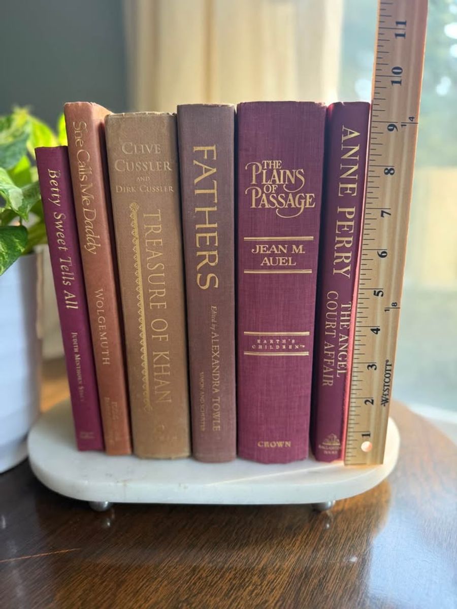 Curated collection of dusty rose, plum, warm brown, taupe, and muted berry-toned books with soft vintage character.