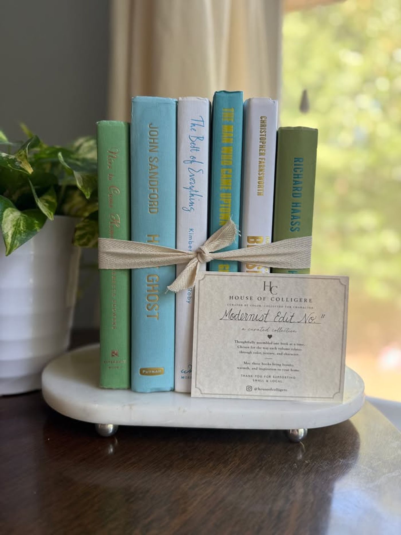 Modernist Edit No. 11 decorative book collection in fresh green, aqua, teal, ivory, and olive tones, tied with neutral linen ribbon and styled on a marble table.