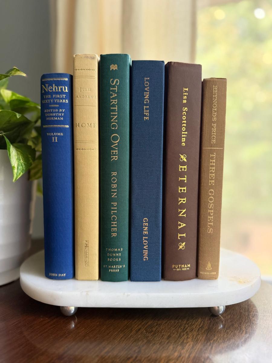 Curated collection of rich brown, hunter green, deep navy, and warm ivory books with classic gold accents.