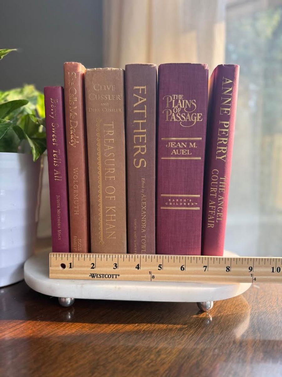 Curated collection of dusty rose, plum, warm brown, taupe, and muted berry-toned books with soft vintage character.