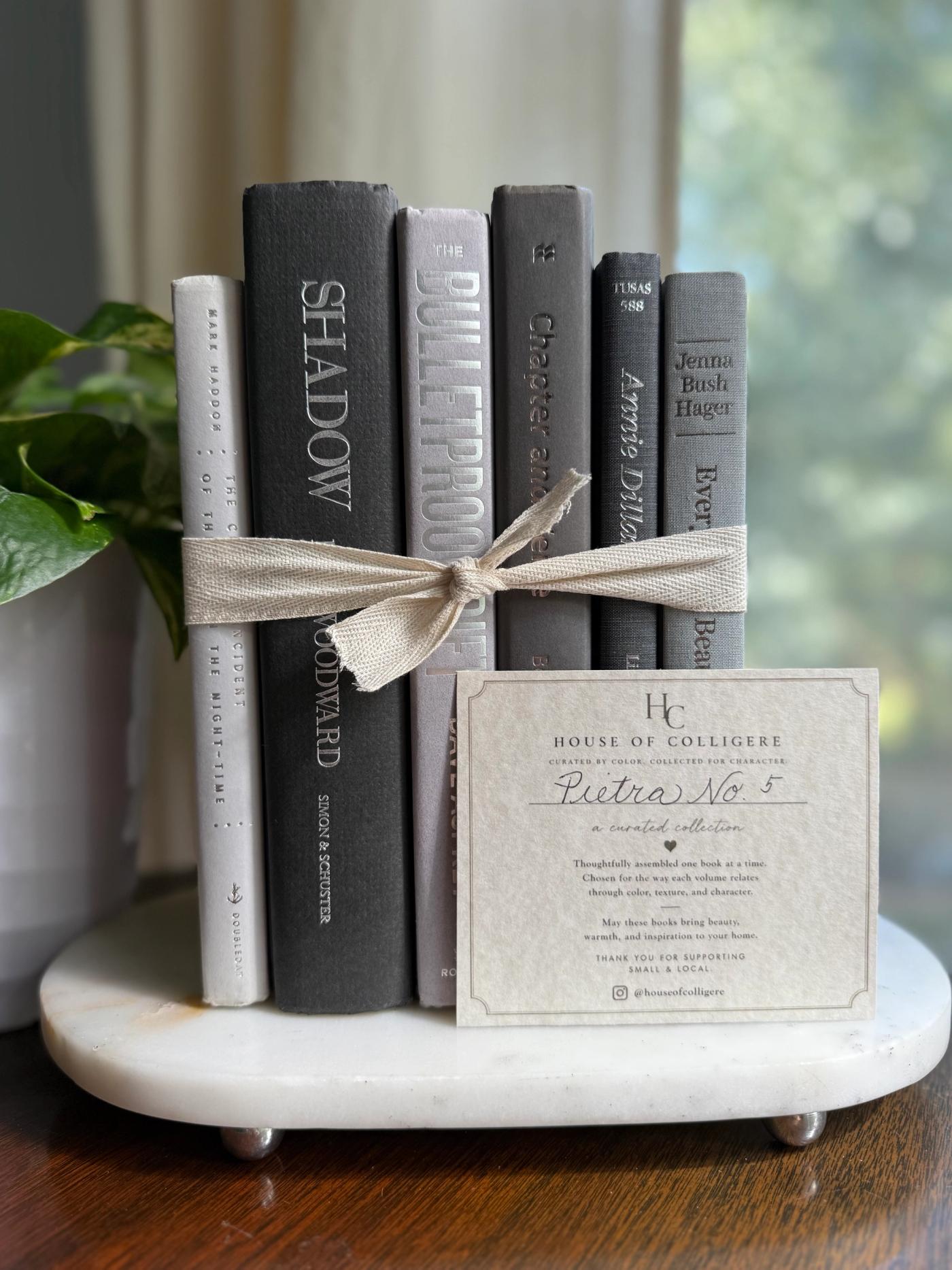 Curated collection of soft white, pale gray, warm greige, and stone-toned books with subtle tonal variation.