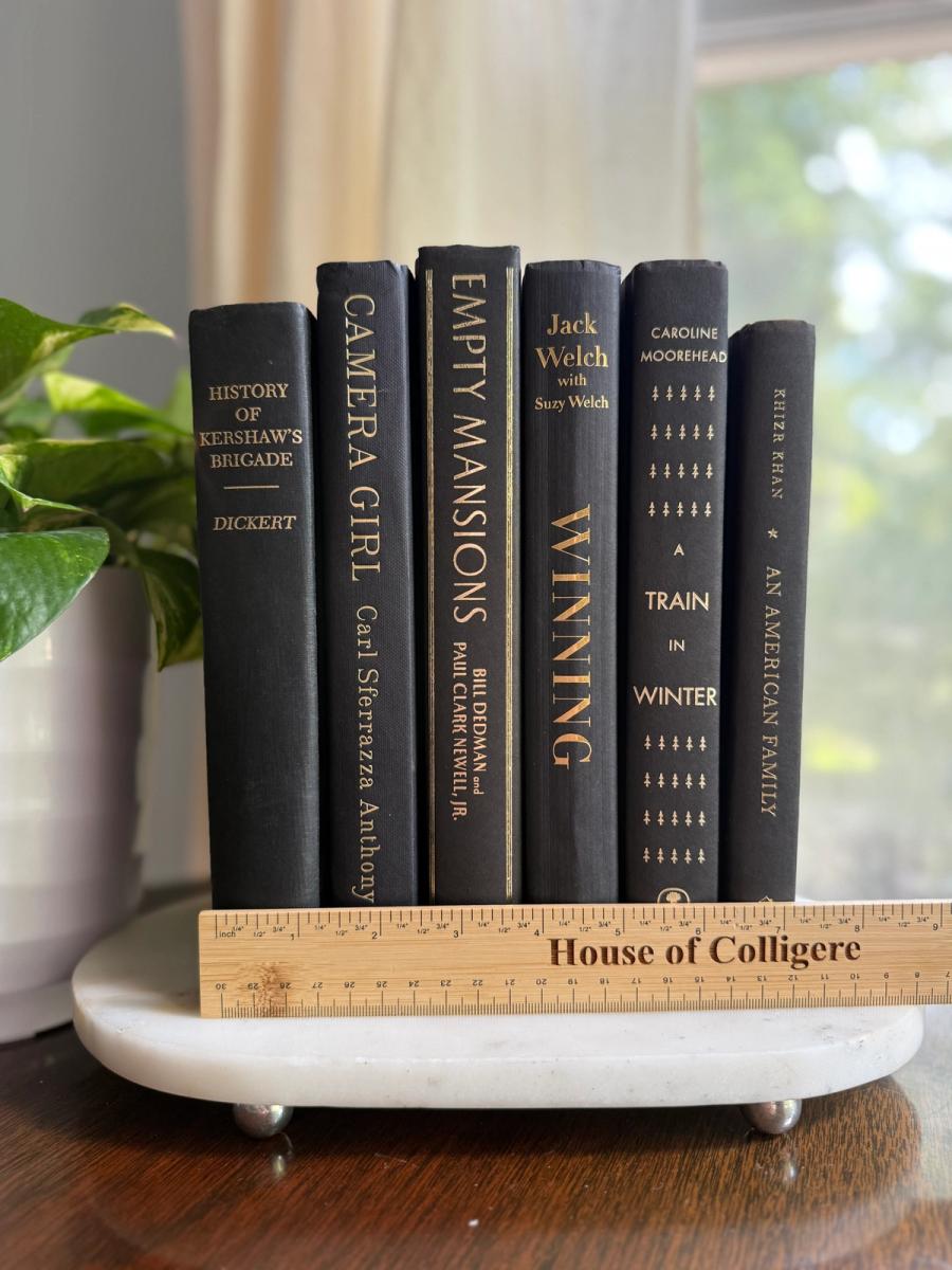 Curated collection of rich charcoal and black books with warm gold lettering and dramatic tonal depth.